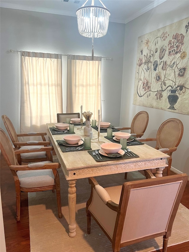 dining space with ornamental molding, an inviting chandelier, and hardwood / wood-style flooring