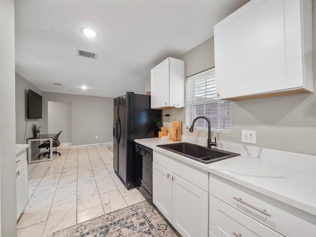 kitchen featuring black dishwasher, sink, light stone counters, and white cabinets