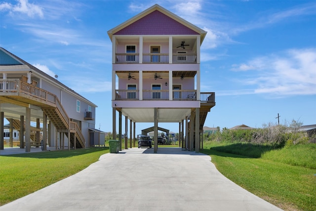 coastal home featuring ceiling fan, a front lawn, covered porch, and a carport