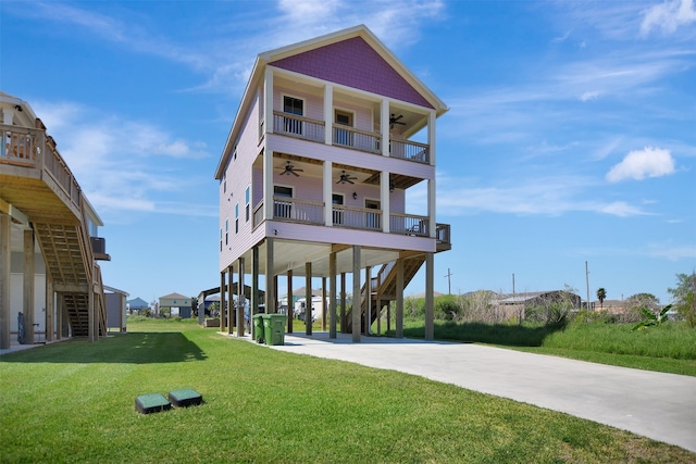 coastal home with a front lawn, ceiling fan, and a carport