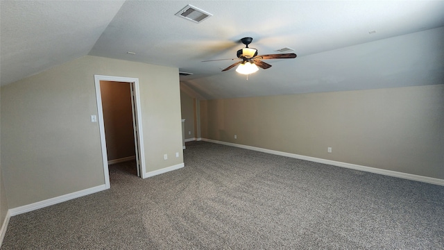 additional living space featuring ceiling fan, a textured ceiling, lofted ceiling, and dark colored carpet