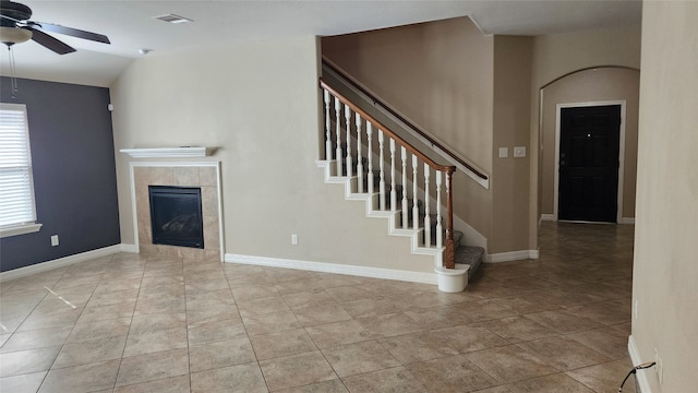 unfurnished living room with a tiled fireplace, light tile patterned flooring, vaulted ceiling, and ceiling fan