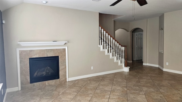 unfurnished living room with tile patterned flooring, a tile fireplace, vaulted ceiling, and ceiling fan