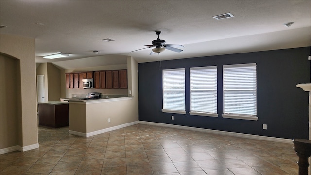 kitchen with appliances with stainless steel finishes, a textured ceiling, light tile patterned floors, and ceiling fan