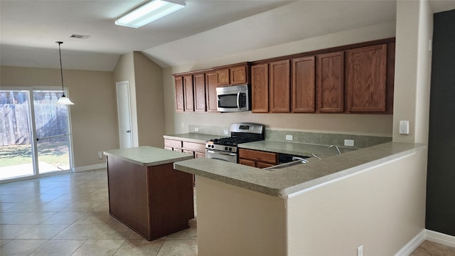 kitchen with lofted ceiling, kitchen peninsula, appliances with stainless steel finishes, pendant lighting, and a center island