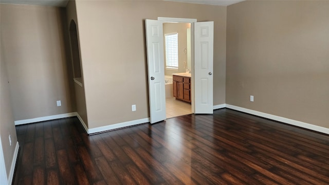 unfurnished bedroom featuring hardwood / wood-style flooring and connected bathroom