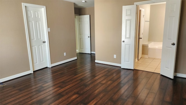 unfurnished bedroom featuring connected bathroom and dark hardwood / wood-style floors