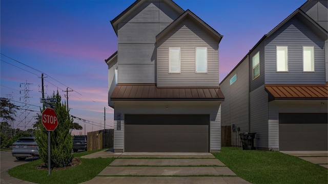 view of front of home featuring concrete driveway, an attached garage, a standing seam roof, metal roof, and fence