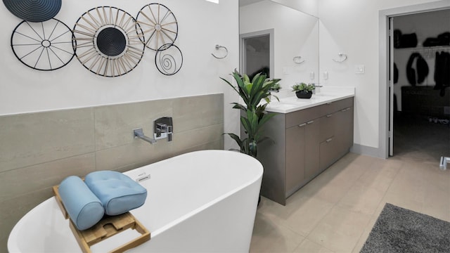 bathroom featuring tile walls, tile patterned floors, a tub, and vanity