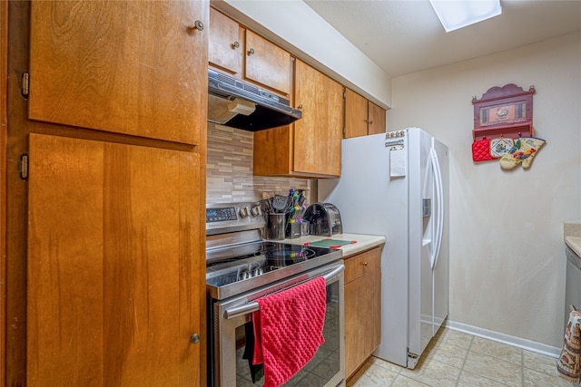 kitchen featuring decorative backsplash, white fridge with ice dispenser, and electric range