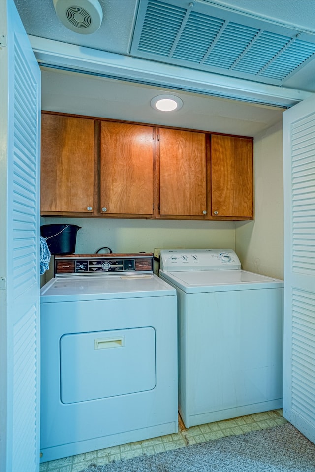 laundry room featuring separate washer and dryer and cabinets