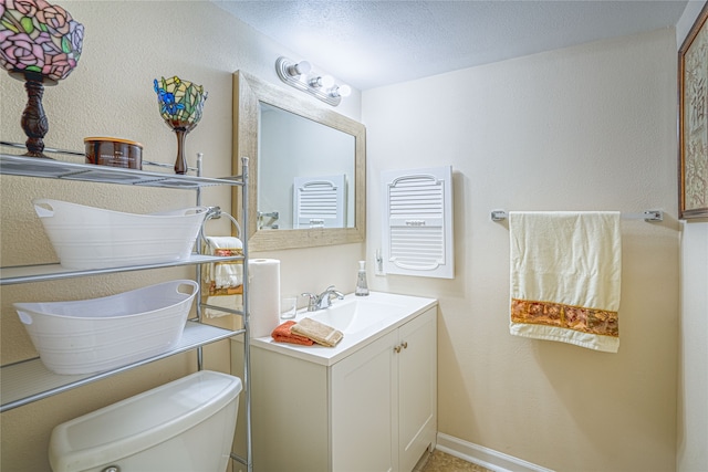 bathroom featuring a textured ceiling, vanity, and toilet