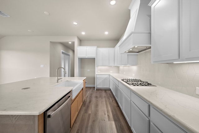 kitchen featuring dark wood-type flooring, light stone countertops, white cabinets, appliances with stainless steel finishes, and premium range hood