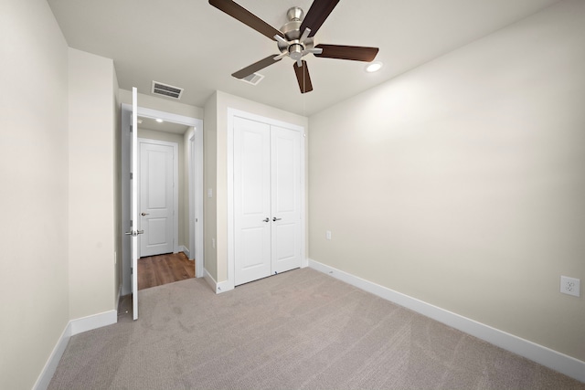 unfurnished bedroom featuring ceiling fan, a closet, and light colored carpet