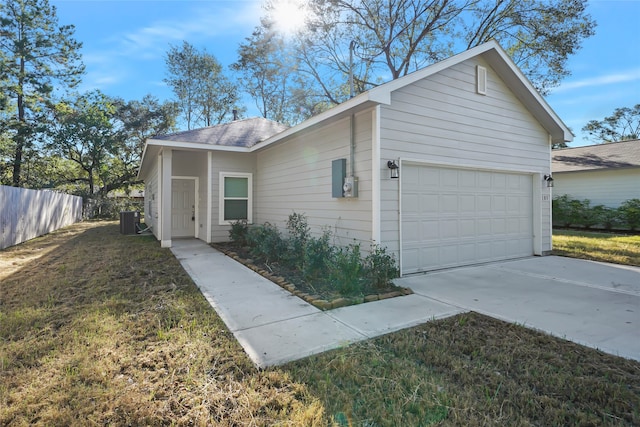 view of side of home with central air condition unit, a lawn, an attached garage, fence, and driveway