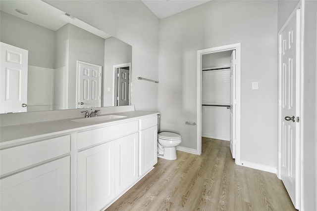 bathroom featuring hardwood / wood-style floors, walk in shower, vanity, and toilet