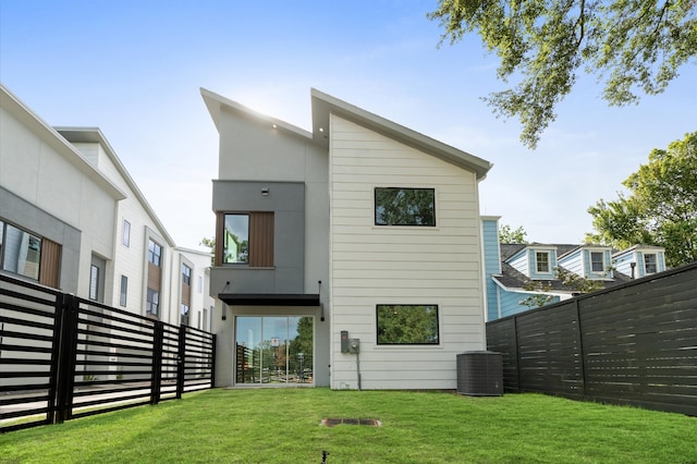 rear view of property featuring central air condition unit and a yard