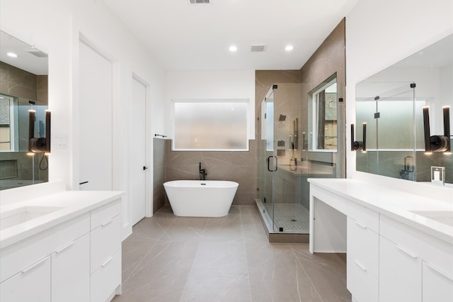 bathroom with plenty of natural light, tile walls, vanity, and independent shower and bath