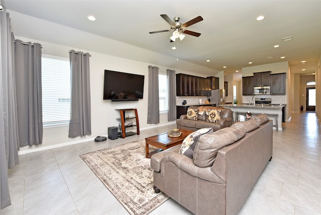 living room featuring light tile patterned flooring, sink, and ceiling fan