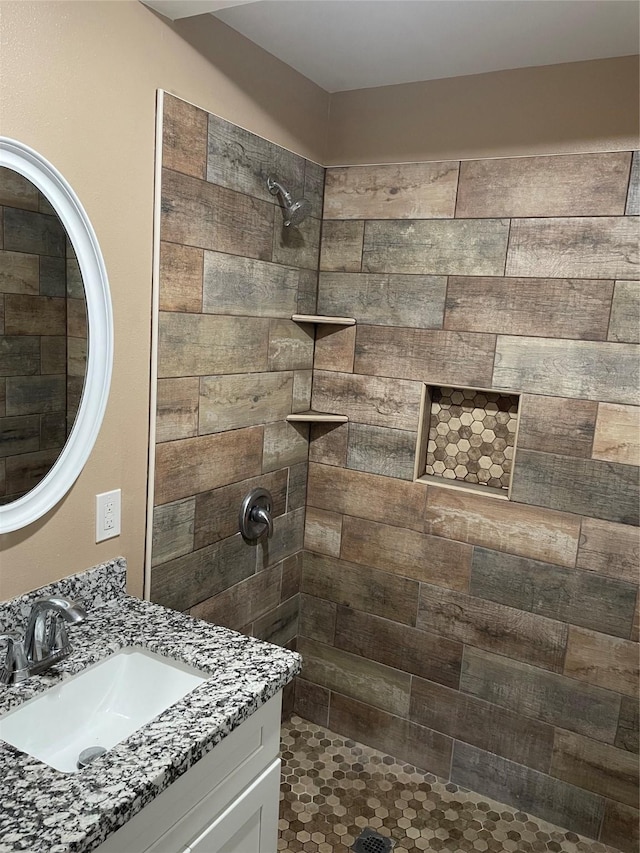 bathroom with tiled shower and vanity