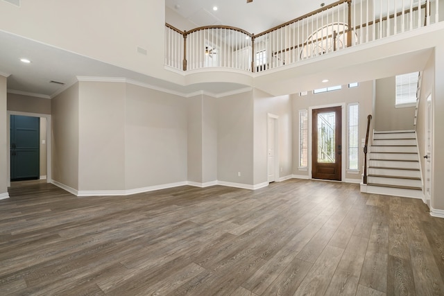 entryway featuring wood-type flooring, a high ceiling, and ornamental molding