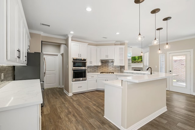 kitchen featuring white cabinets, pendant lighting, stainless steel appliances, dark hardwood / wood-style flooring, and decorative backsplash