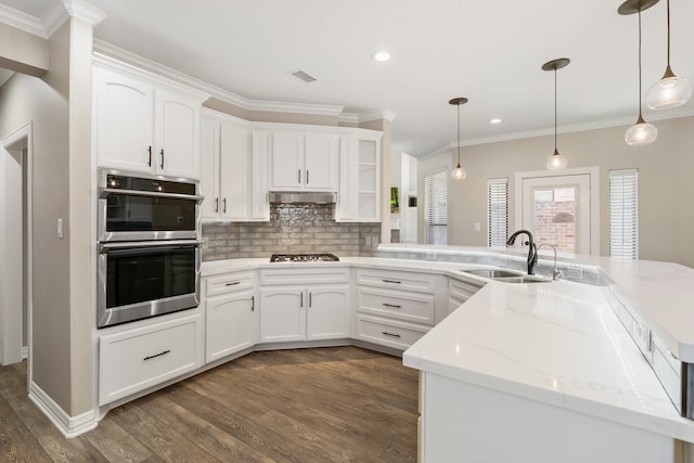 kitchen featuring appliances with stainless steel finishes, hanging light fixtures, dark wood-type flooring, white cabinets, and sink