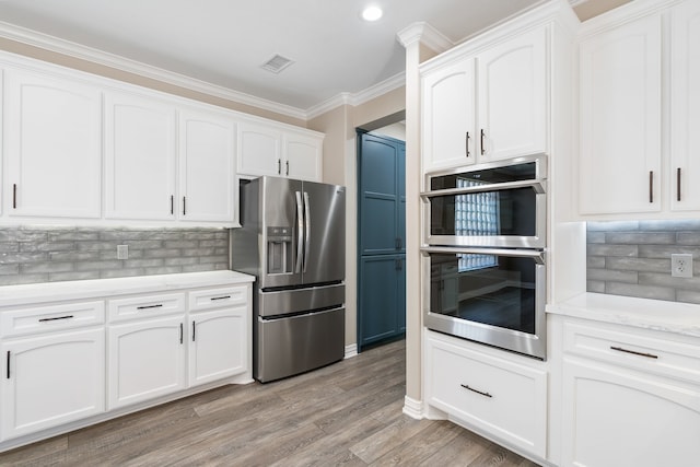 kitchen featuring ornamental molding, backsplash, white cabinetry, appliances with stainless steel finishes, and light hardwood / wood-style floors