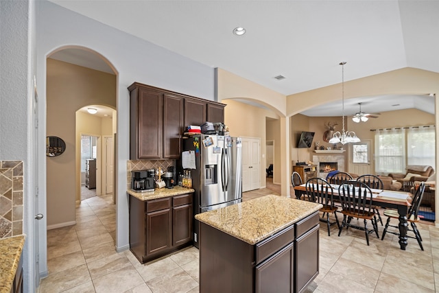 kitchen featuring dark brown cabinetry, a center island, pendant lighting, and light stone counters