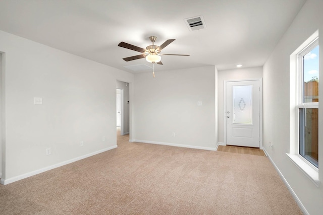 empty room with ceiling fan and light carpet