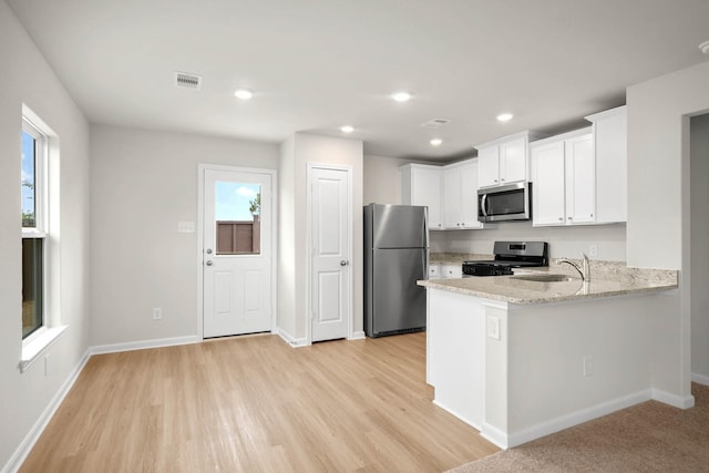 kitchen featuring white cabinets, sink, appliances with stainless steel finishes, light stone counters, and kitchen peninsula