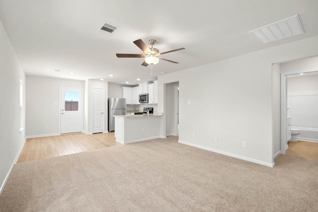 unfurnished living room featuring ceiling fan and light colored carpet