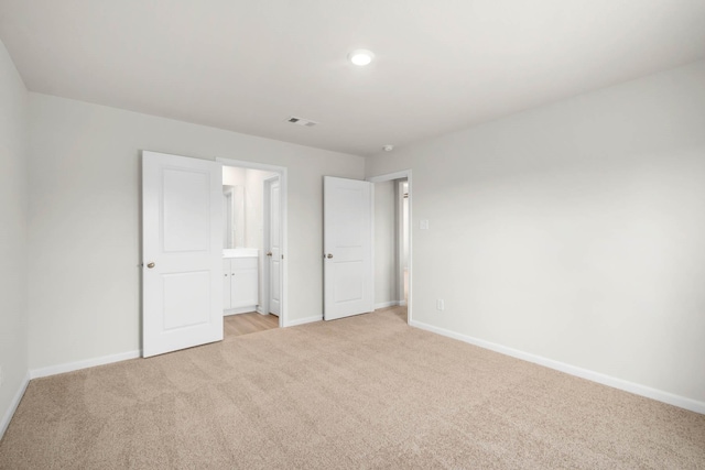 unfurnished bedroom with light colored carpet and ensuite bath