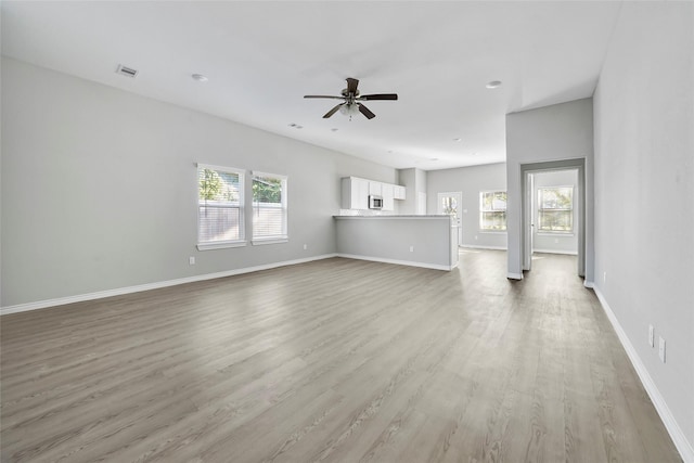 unfurnished living room featuring ceiling fan, plenty of natural light, and light hardwood / wood-style flooring