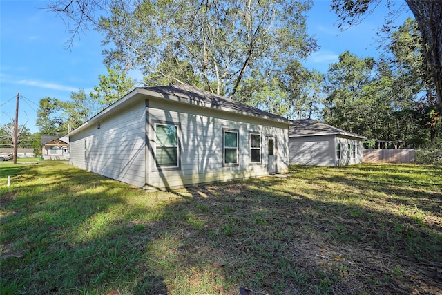 rear view of house with a lawn and fence