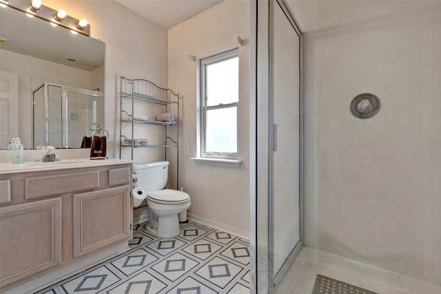 bathroom featuring tile patterned floors, vanity, a shower with shower door, and toilet