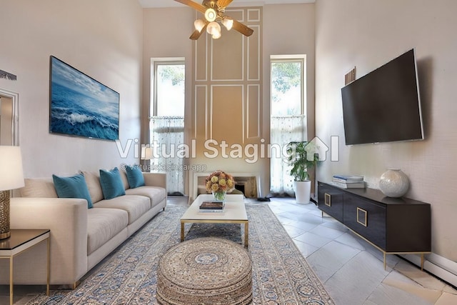 living room featuring ceiling fan, plenty of natural light, and a towering ceiling