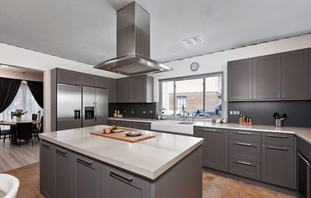 kitchen with island exhaust hood, gray cabinetry, a kitchen island, and stainless steel appliances