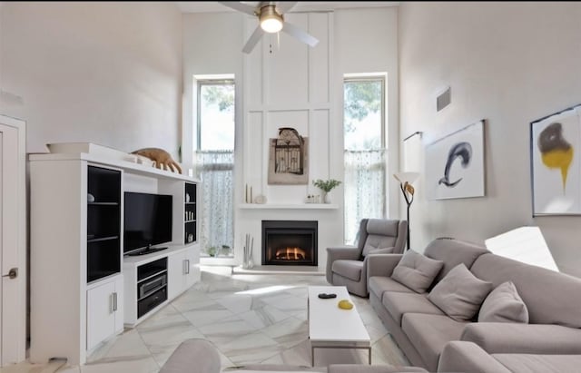 living room with a towering ceiling, a wealth of natural light, and ceiling fan