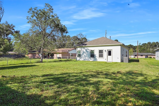 rear view of property featuring cooling unit and a yard