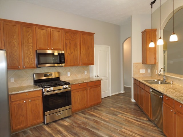 kitchen with sink, decorative light fixtures, backsplash, appliances with stainless steel finishes, and dark hardwood / wood-style floors