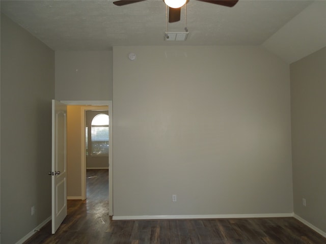 empty room featuring a textured ceiling, lofted ceiling, ceiling fan, and dark wood-type flooring