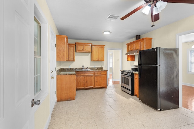 kitchen with ceiling fan, black fridge, sink, stainless steel range with gas cooktop, and light hardwood / wood-style floors