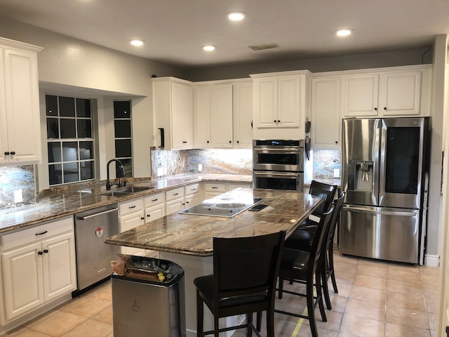 kitchen featuring a kitchen breakfast bar, kitchen peninsula, white cabinets, and stainless steel appliances