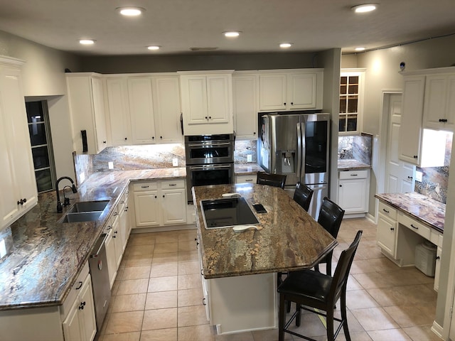 kitchen with white cabinets, a kitchen breakfast bar, stainless steel appliances, sink, and a center island