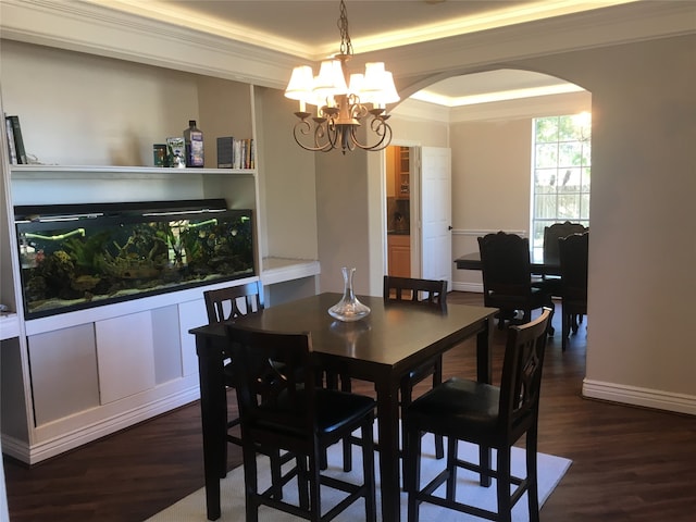 dining area featuring crown molding, a tray ceiling, a notable chandelier, and dark hardwood / wood-style flooring