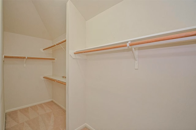 spacious closet with lofted ceiling and light carpet