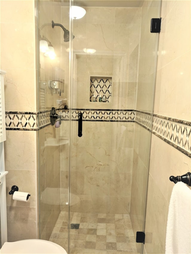 bathroom featuring toilet and a shower with shower door