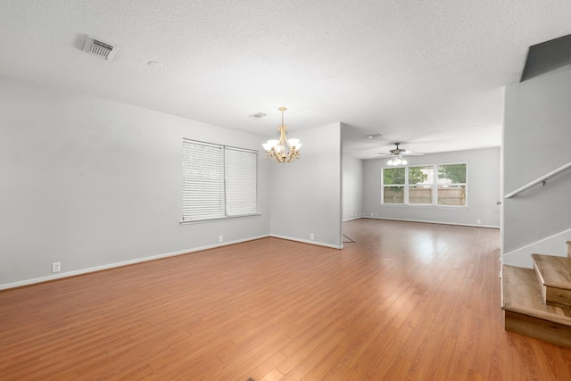 empty room featuring ceiling fan with notable chandelier, a textured ceiling, and hardwood / wood-style flooring