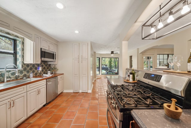 kitchen featuring decorative backsplash, white cabinets, appliances with stainless steel finishes, and plenty of natural light